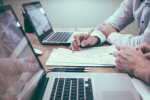 two people working with laptop and notepads